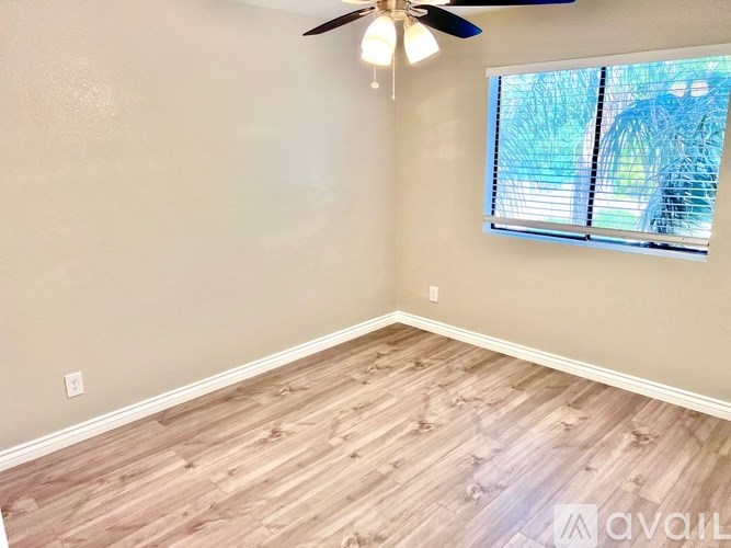 A room with a ceiling fan and a window with blinds.