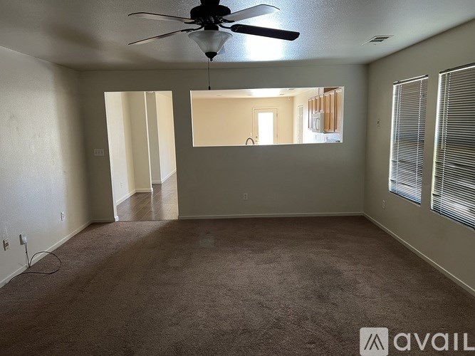 A room with a ceiling fan and carpeted floor.