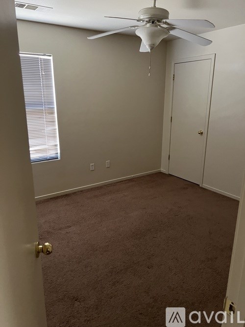 A room with a ceiling fan and carpeted floor.