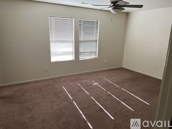 A room with a carpeted floor and a ceiling fan.