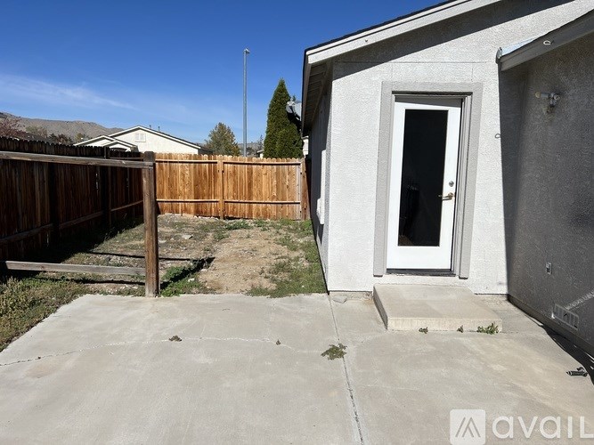A backyard with a white door and a wooden fence.