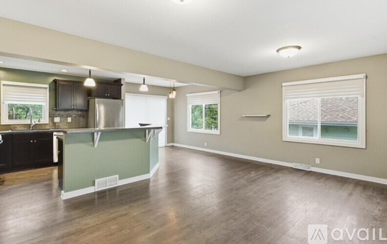 A spacious kitchen with a refrigerator, cabinets, and a window.