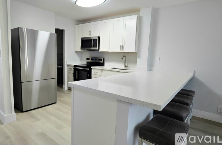 A kitchen with a white counter and black stools.