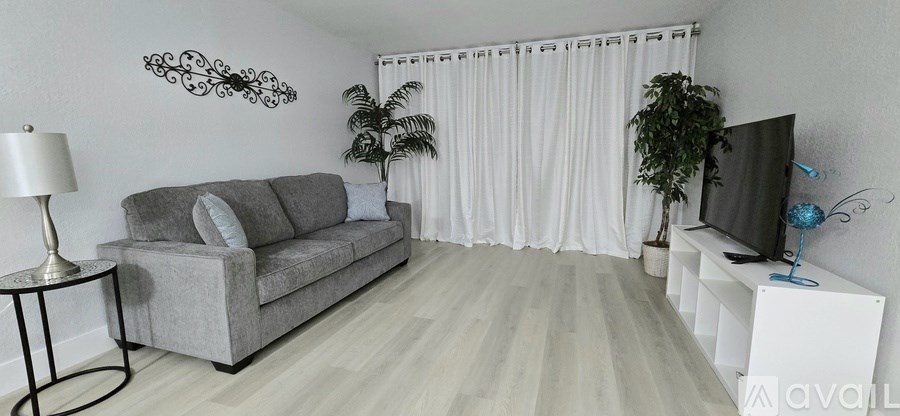 A living room with a grey sofa, a television, and a plant.