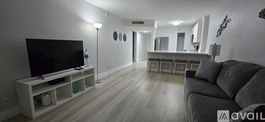 A living room with a grey couch and a television on a stand.