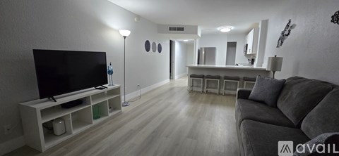 A living room with a grey couch and a television on a stand.