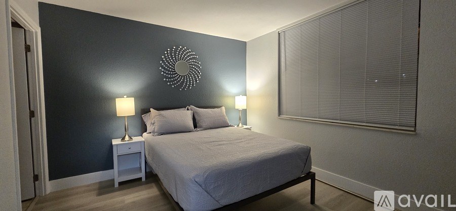 A bedroom with a bed, two lamps, and a wall decoration.