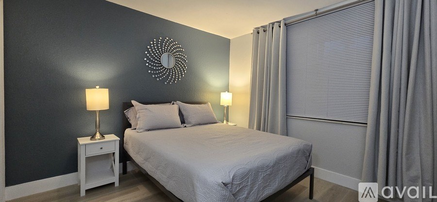 A bedroom with a bed, nightstand, and wall decor.