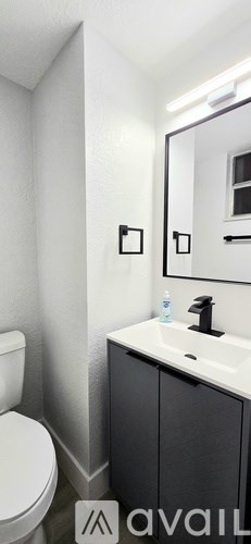 A bathroom with a white toilet and a white sink with a black faucet.