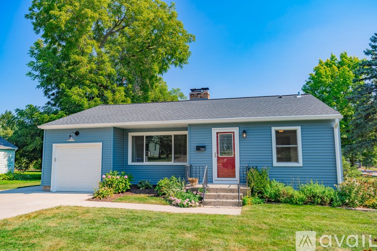A blue house with a red door and a white garage door.