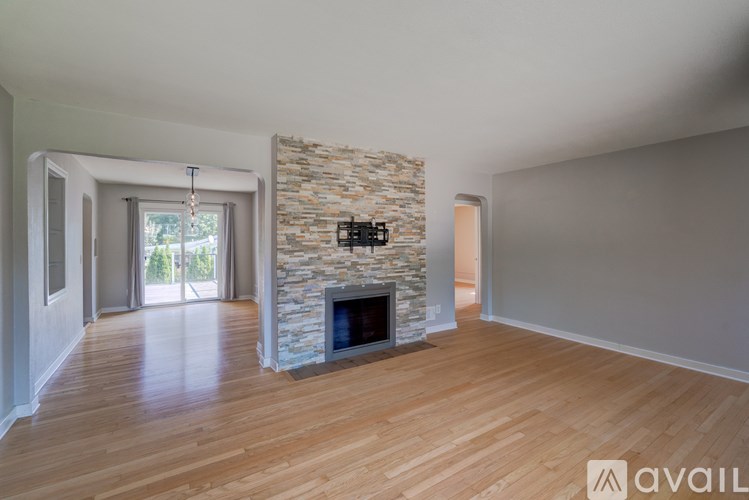 A spacious living room with a stone fireplace and wooden flooring.