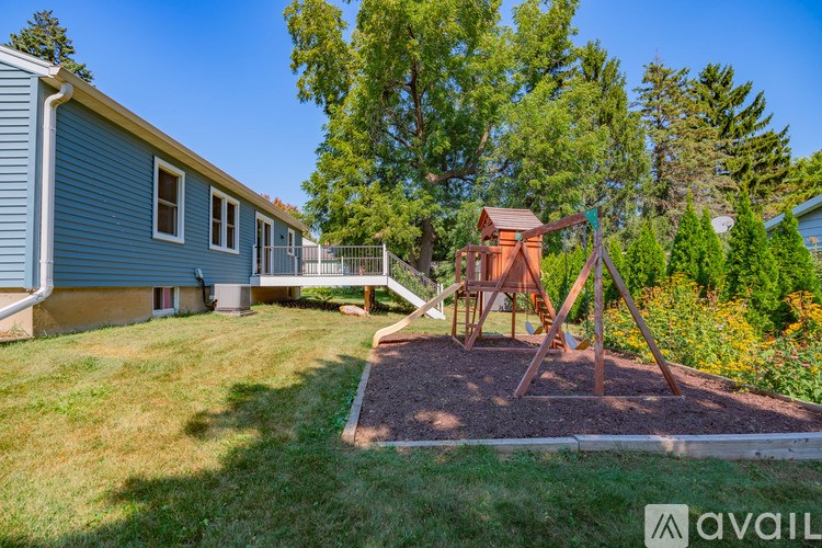 A playground with a swing set is in the foreground of a residential area.