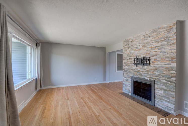 A room with a stone fireplace and wooden flooring.