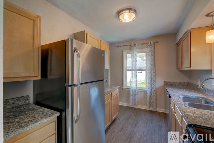 A kitchen with a refrigerator, sink, and cabinets.