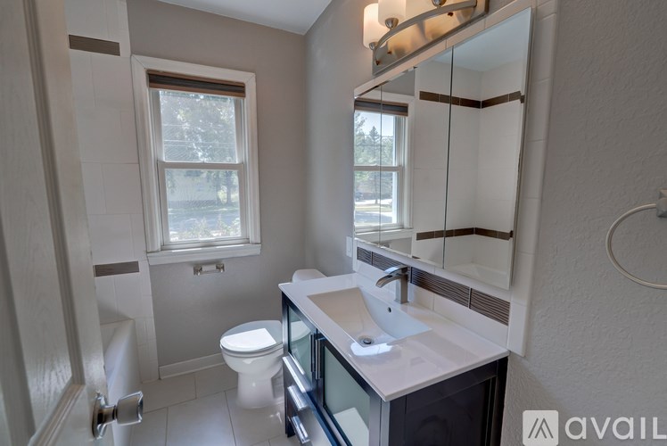 A bathroom with a toilet, sink, and mirror.