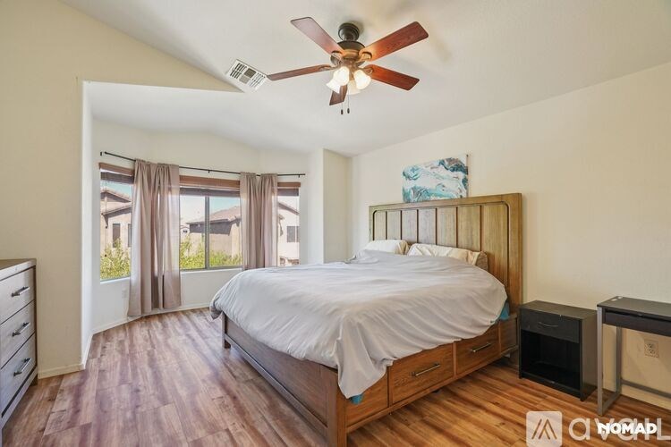 A bedroom with a bed, dresser, and window with curtains.