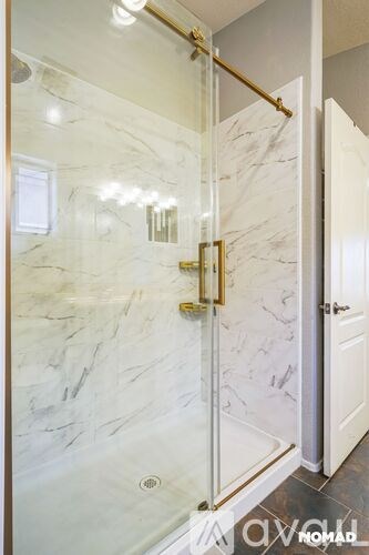 A bathroom with a marble wall and a glass shower door.