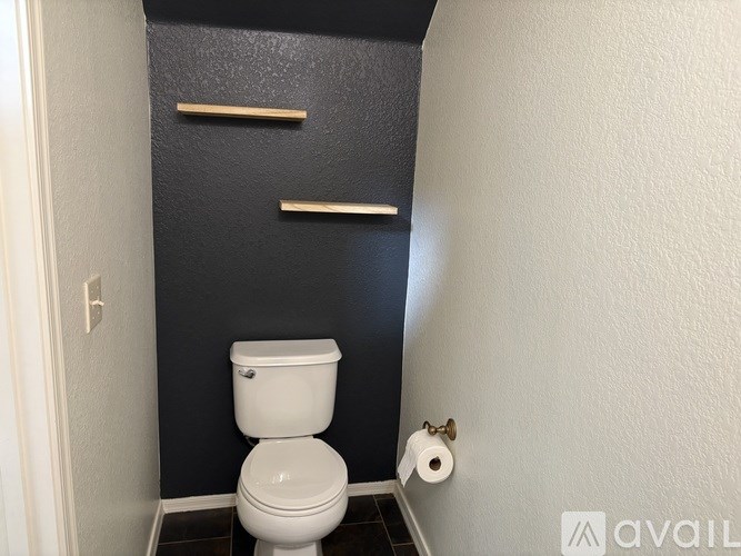 A white toilet in a small bathroom with a black door.
