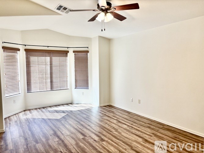 A room with a ceiling fan and wooden flooring.
