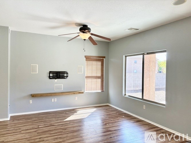 A room with a ceiling fan and a window with blinds.