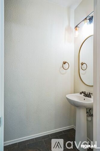 A white sink with a gold rimmed mirror above it.