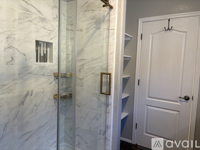 A bathroom with marble tiles and a glass shower door.