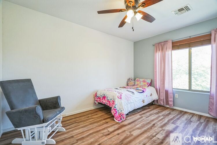A bedroom with a bed, chair, and window.