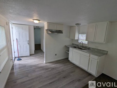 A kitchen with white cabinets and a grey countertop.