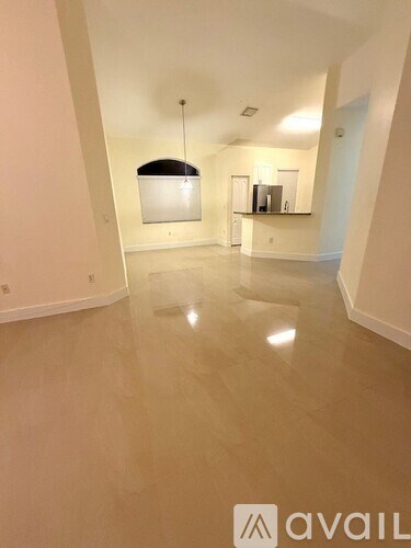 A spacious room with a light hanging from the ceiling and a counter in the background.