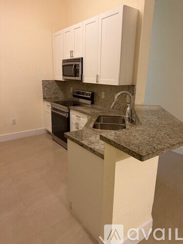 A kitchen with granite countertops and white cabinets.