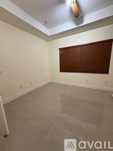 A room with a brown blind on the window and a tiled floor.