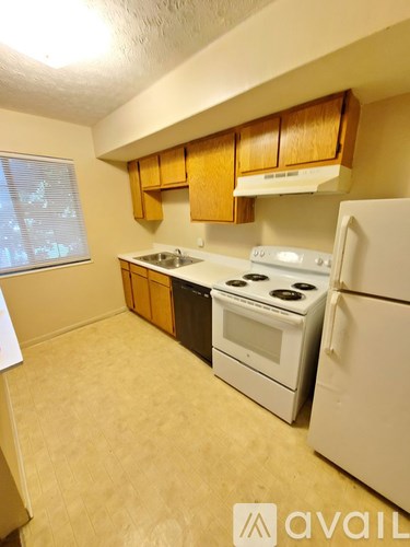 A kitchen with a white fridge, white stove and white sink.