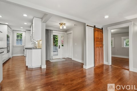 A spacious kitchen with white cabinets and a wooden floor.