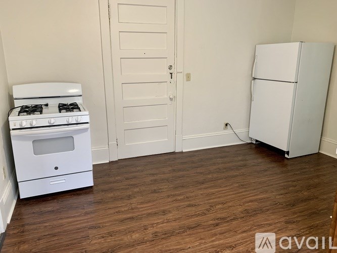A white stove and refrigerator in a room with wooden floors and white walls.