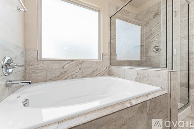 A white bathtub in a bathroom with marble tiles.
