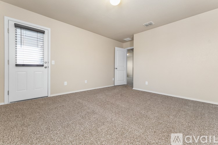 A room with a carpeted floor and a door on the left side.