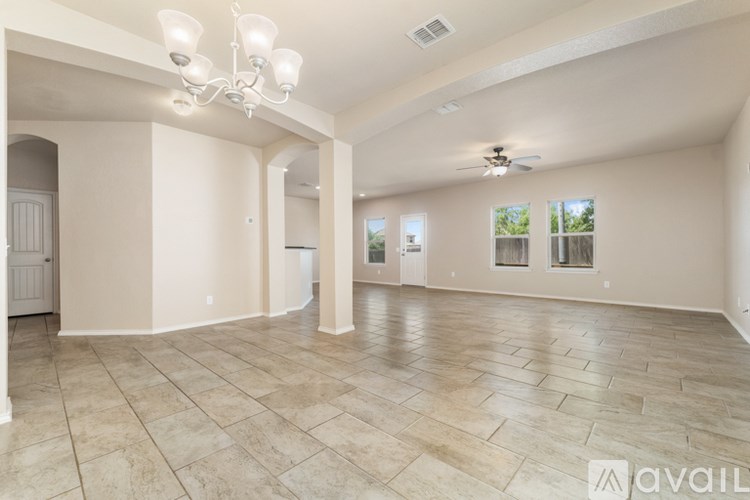 A spacious living room with tiled flooring and a chandelier.