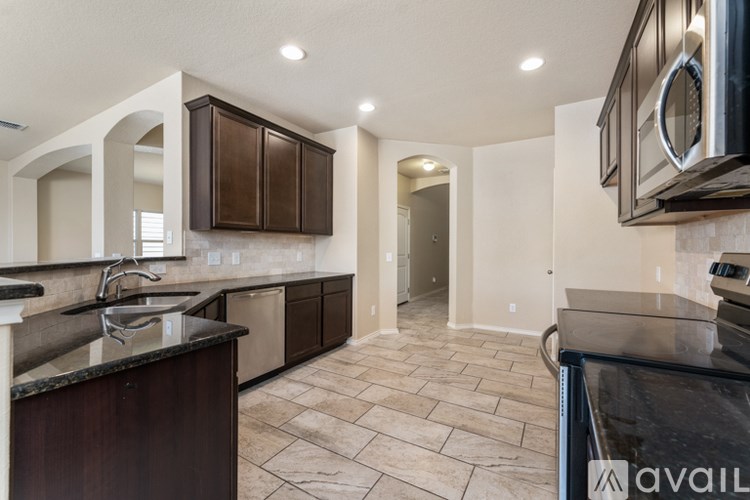 A kitchen with dark brown cabinets and a black countertop.