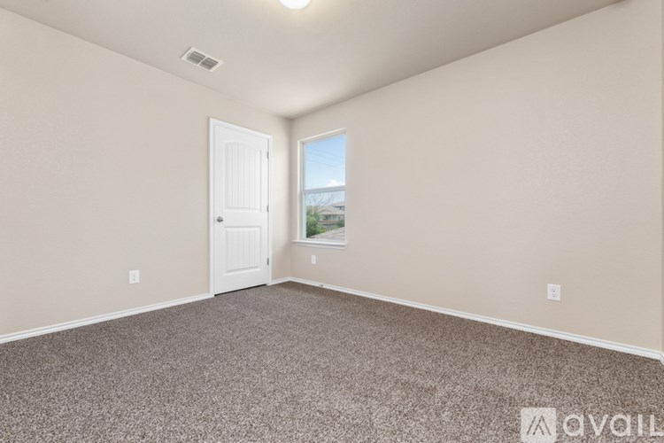 A room with a carpeted floor and a door leading to a balcony.