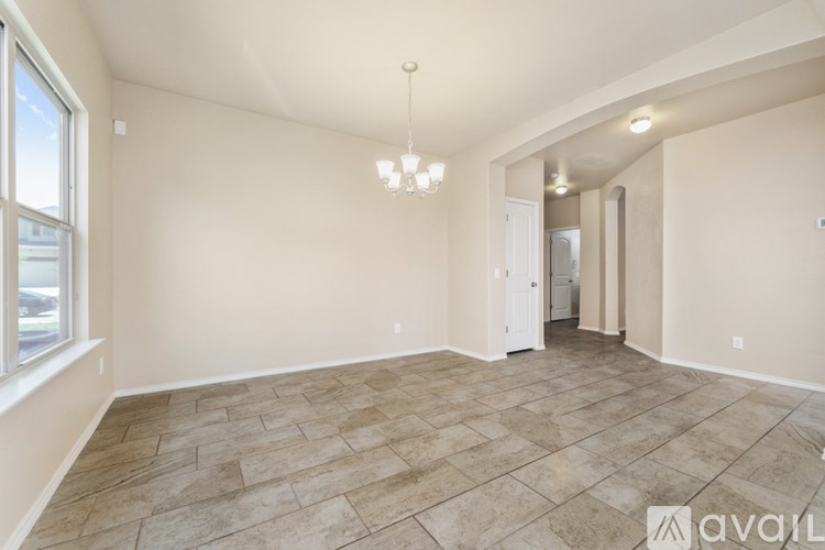 A spacious room with tiled flooring and a chandelier hanging from the ceiling.