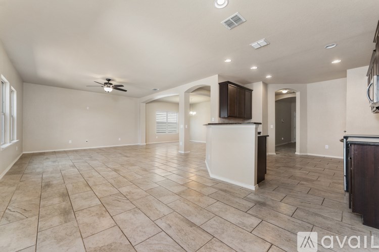 A spacious living room with a kitchen area in the background.
