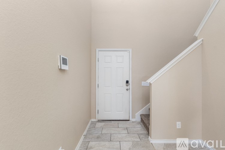 A white door is in a hallway with a stone floor.