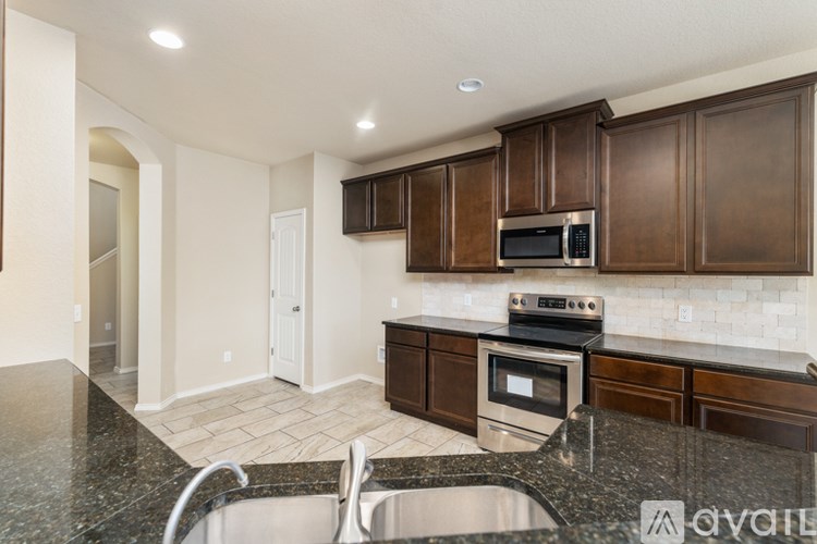 A kitchen with brown cabinets and a black granite countertop.