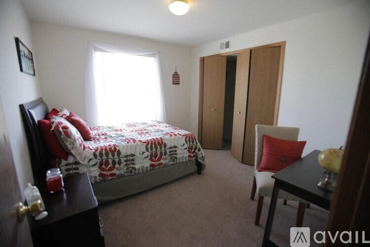 A bedroom with a bed, chair, and table.