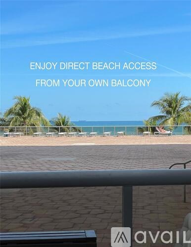 A beachfront balcony with a view of the ocean and palm trees.