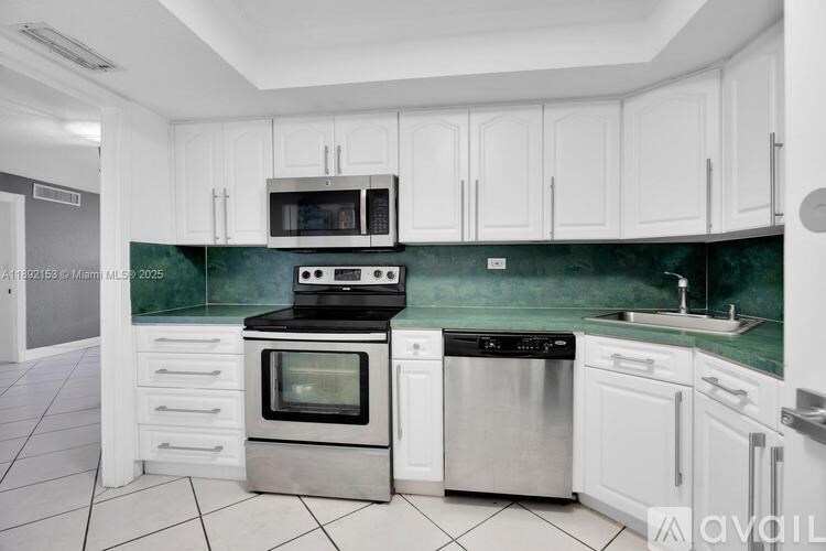 A kitchen with white cabinets and a green backsplash.