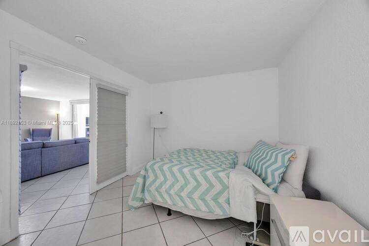 A bedroom with a bed and a couch in the background.