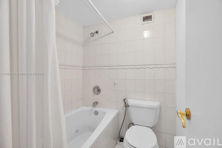 A white bathroom with a toilet, tub, and shower.