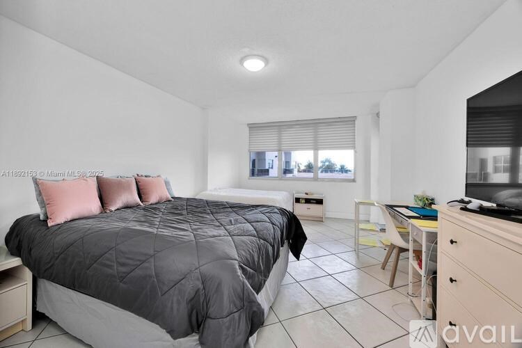 A bedroom with a large bed and a desk with a chair.