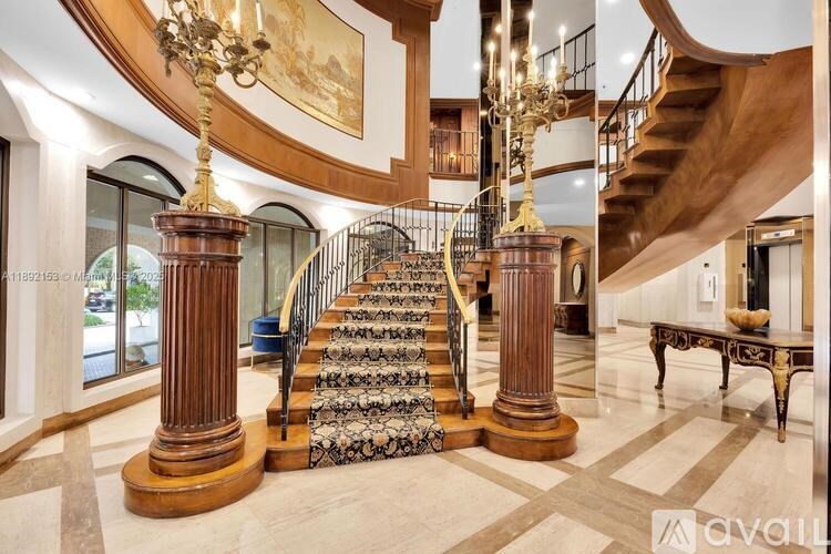 A grand staircase with a chandelier and two large columns.